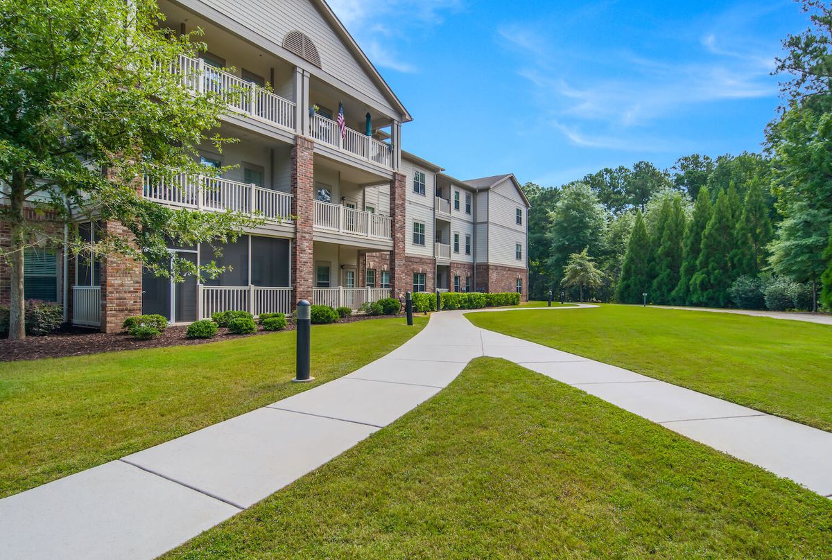 A modern apartment complex with a well-maintained lawn and a winding pathway.