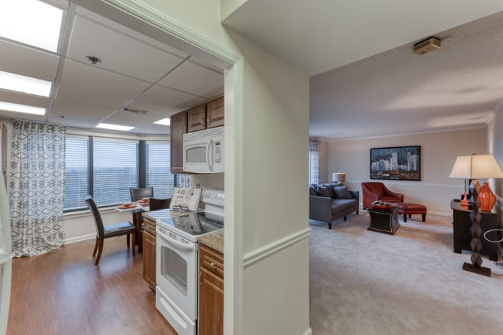 A cozy apartment interior featuring a kitchen with wooden cabinets, an adjacent dining area, and a spacious living room.