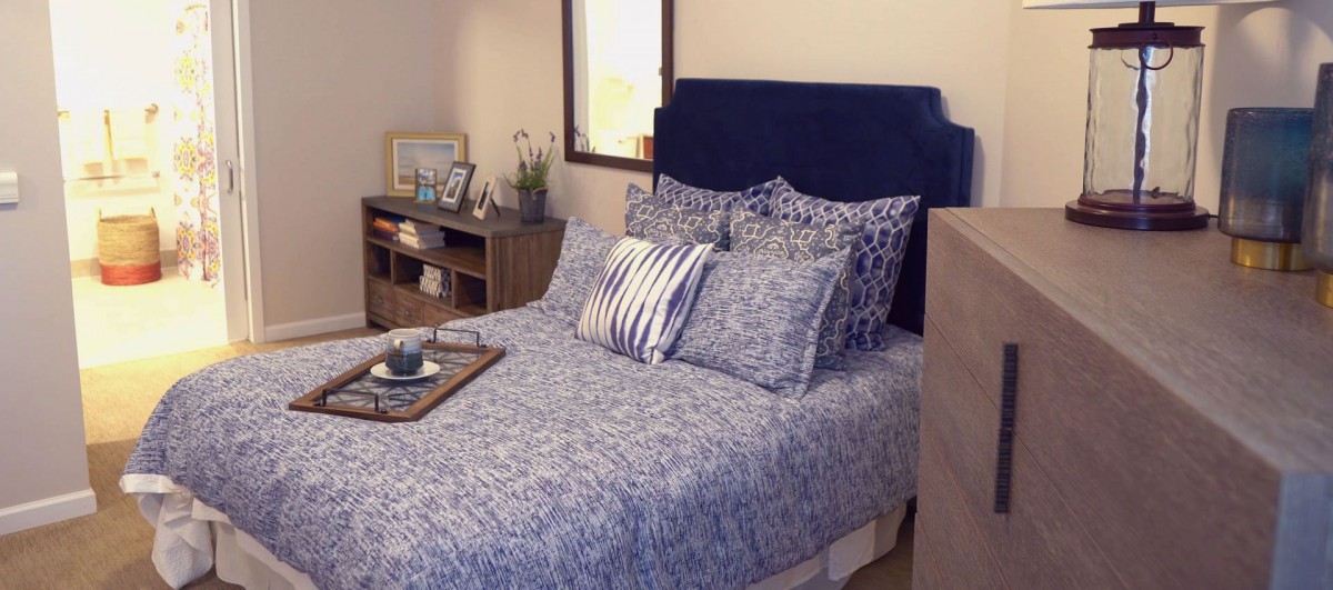 A cozy bedroom with a blue-themed bed and decorative pillows.