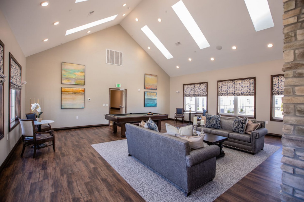 A spacious, modern living room with high ceilings and ample natural light from skylights, featuring comfortable seating and elegant decor.