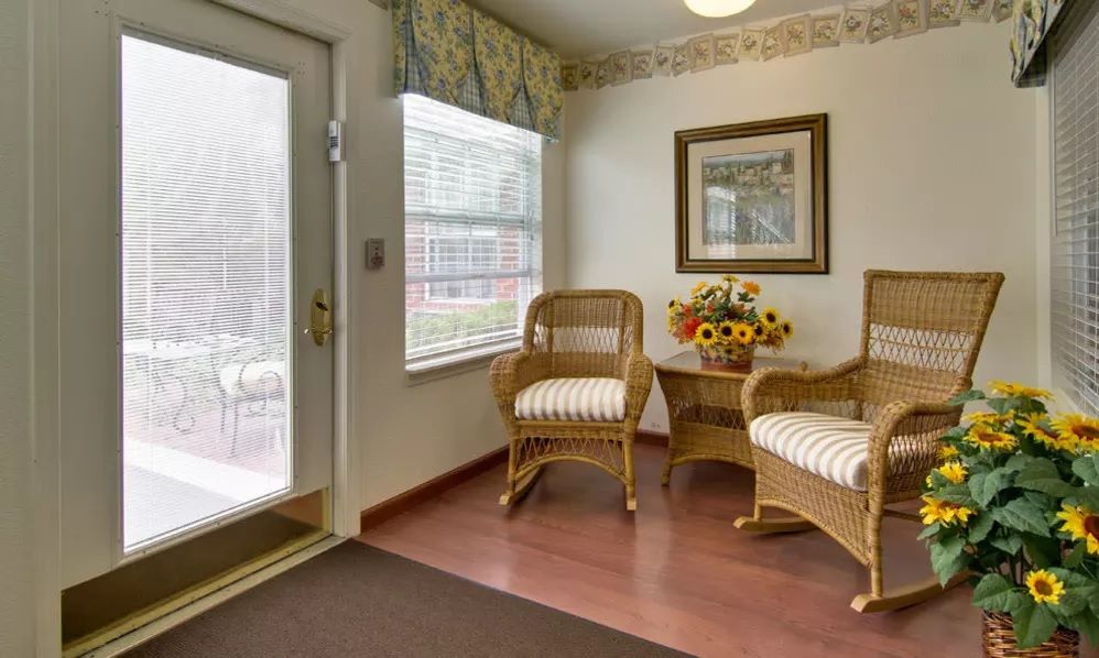 Cozy waiting area with wicker chairs and floral decor by a window.