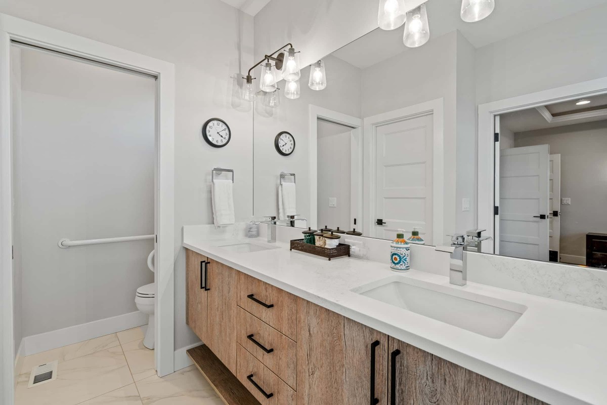 A modern bathroom featuring a dual-sink vanity with ample storage, bright lighting fixtures, and stylish decor.