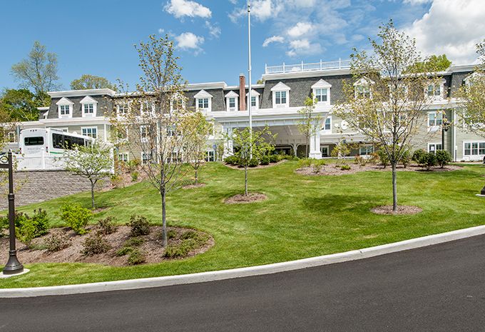 A landscaped view of a large building with manicured lawns and trees under a partly cloudy sky.
