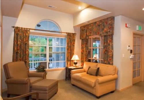 A cozy living room with a sofa, armchair, and warmly lit lamp by the window.