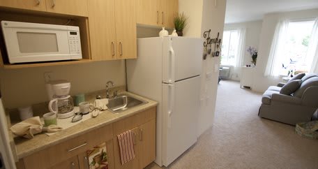 A compact kitchen area with a refrigerator, sink, and wooden cabinets.