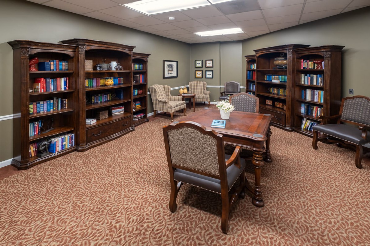 A cozy library room with bookshelves, a wooden table, and chairs.