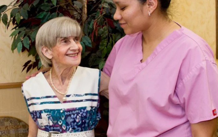 A caregiver providing support to an elderly woman.