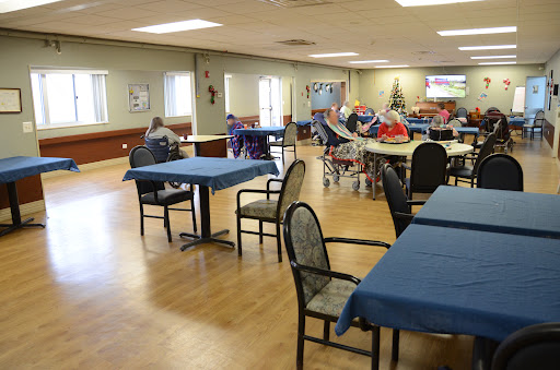 A spacious dining area in a community center, featuring tables with blue tablecloths and ample seating.