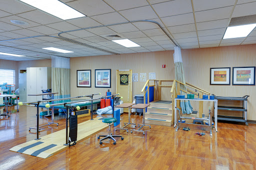 A well-equipped physical therapy room designed for rehabilitation, featuring various exercise tools and a spacious layout.