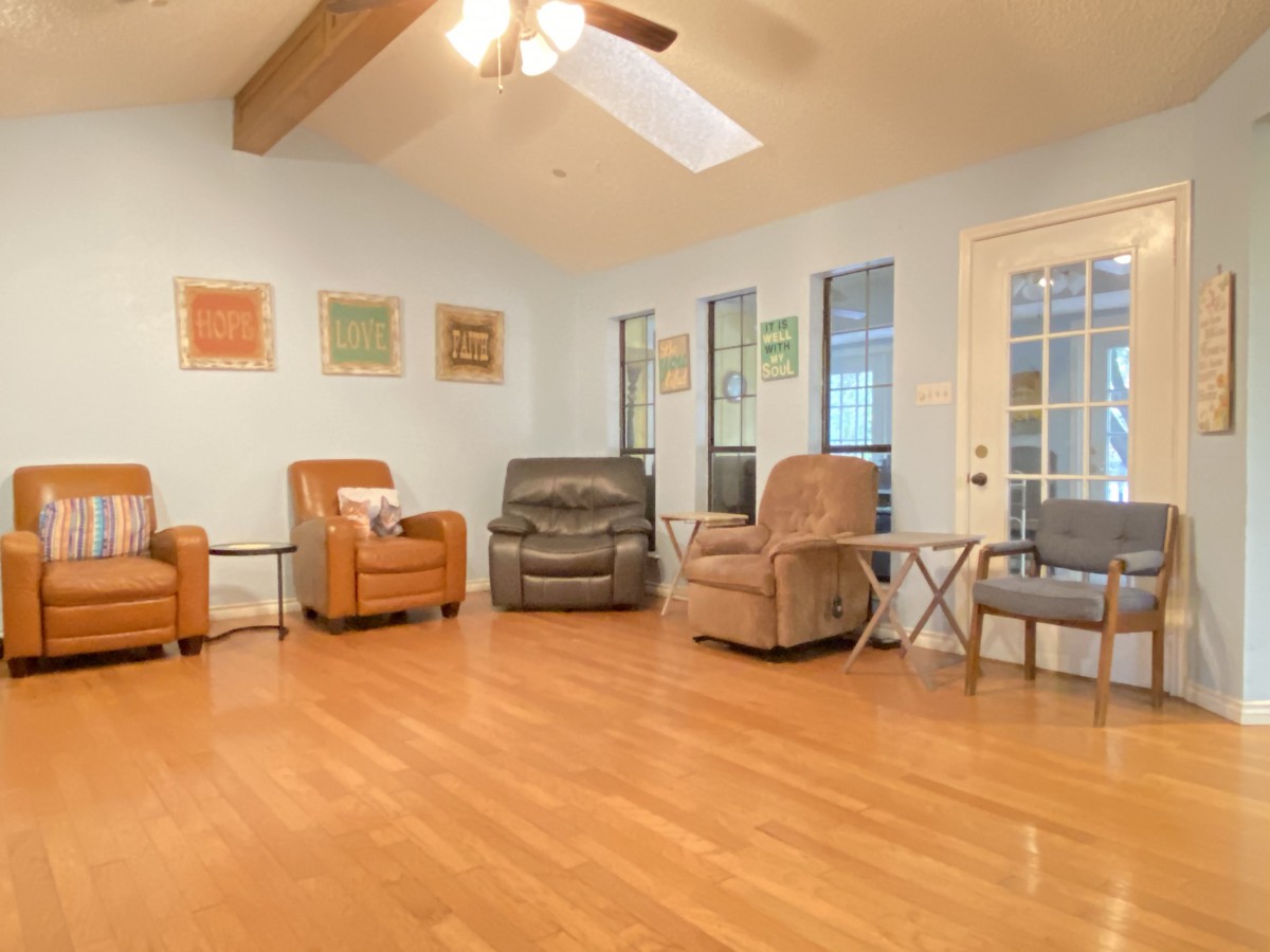 A cozy living room with multiple armchairs and a ceiling fan.
