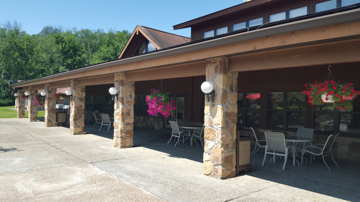 A porch with stone pillars and outdoor seating, featuring balloons for decoration.