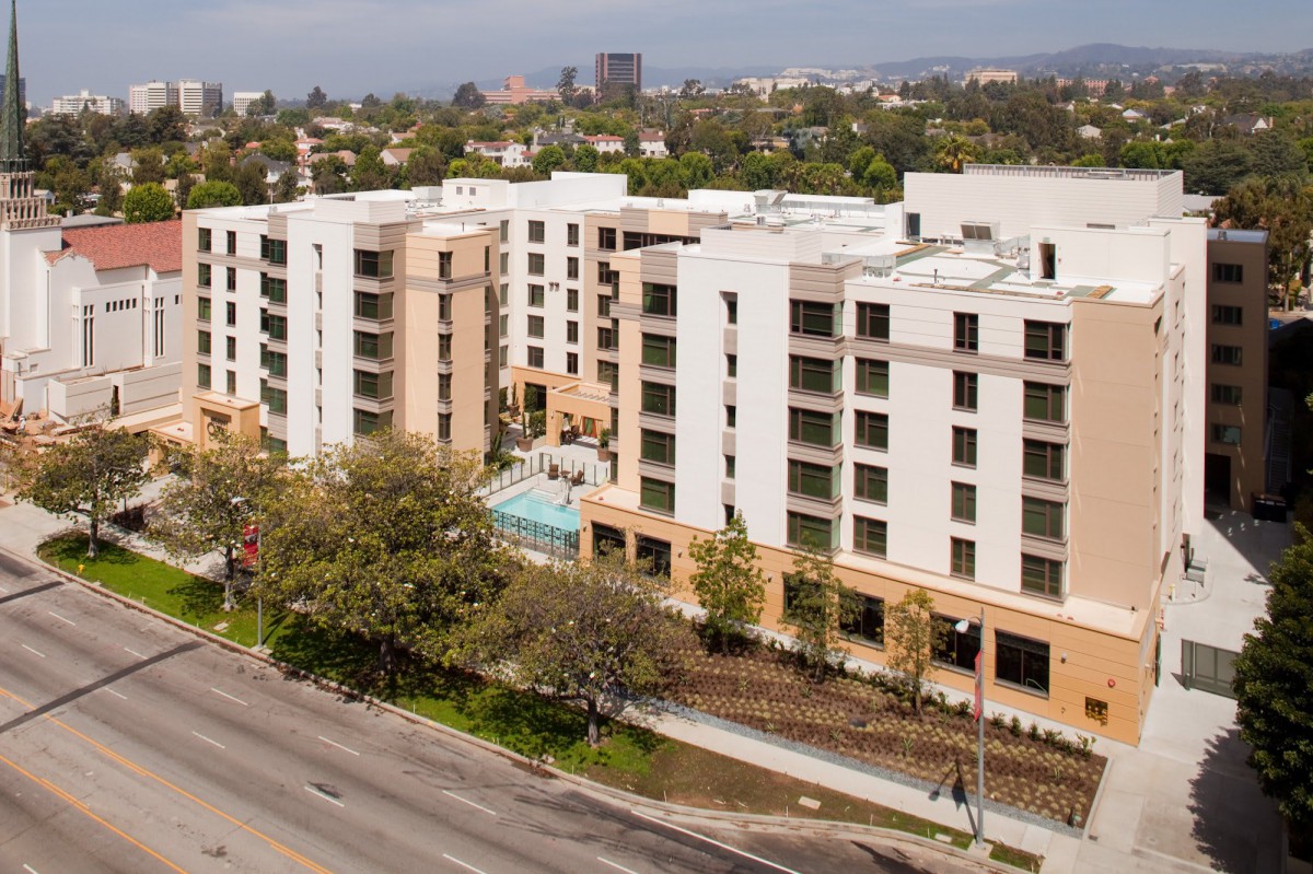 A modern apartment building in an urban setting with a street view.