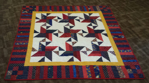 A beautifully crafted quilt featuring a geometric star pattern in red, white, blue, and yellow colors.