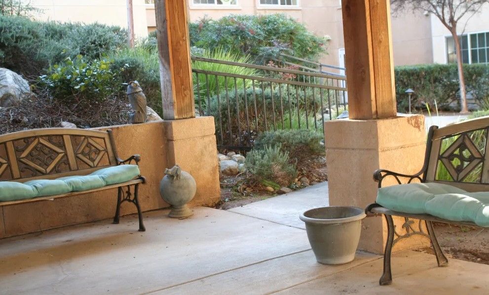 A serene porch area with benches and decorative planters, overlooking a lush garden.