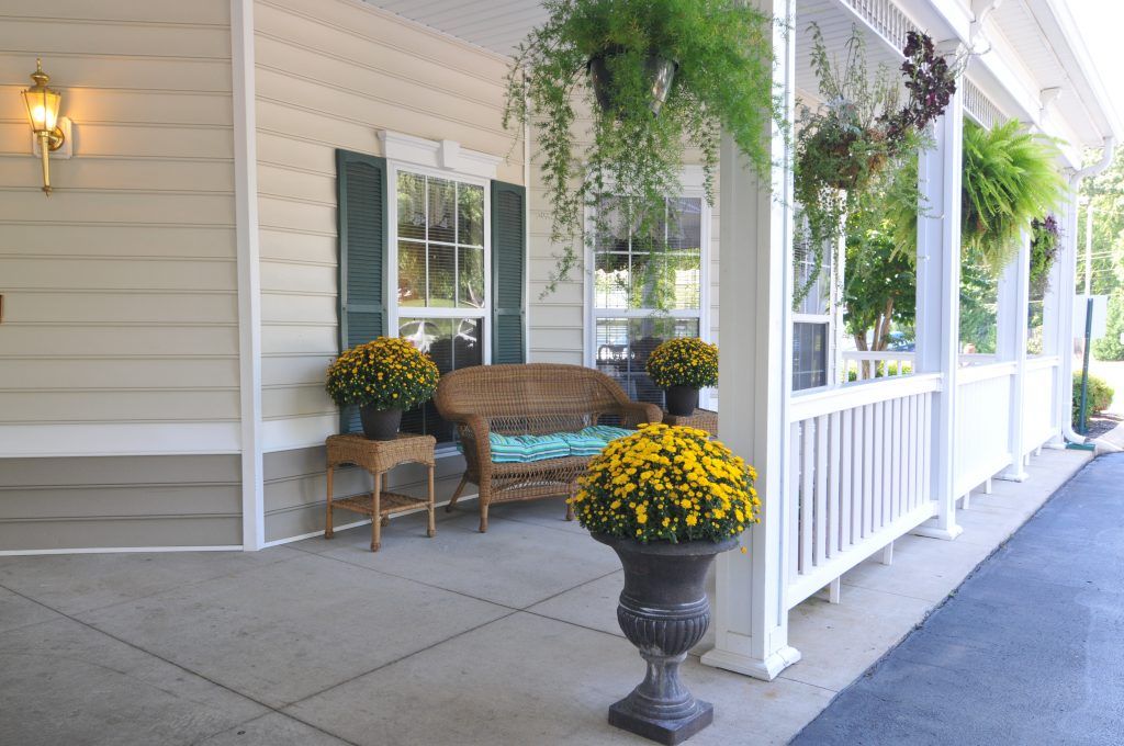 A cozy front porch with a bench and vibrant flowers in pots.