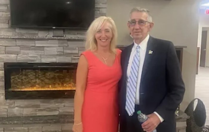 A man and woman posing together in formal attire indoors.