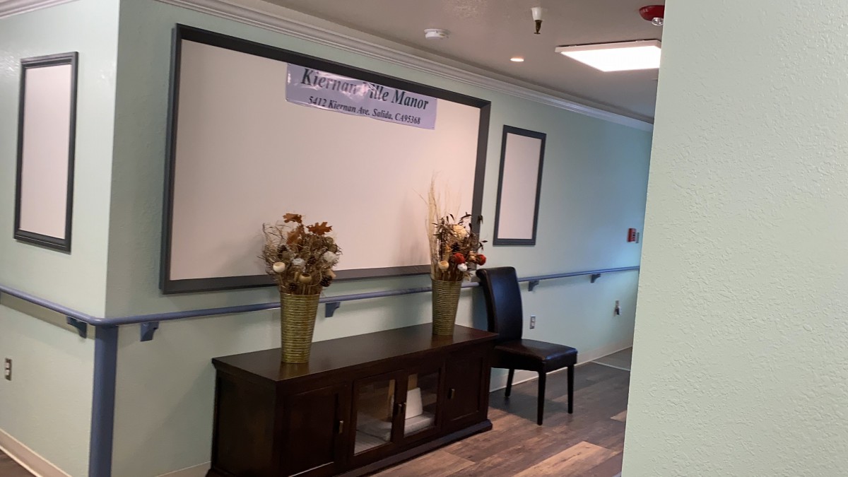 A hallway with decorative furnishings, including a table, chair, and floral arrangements.