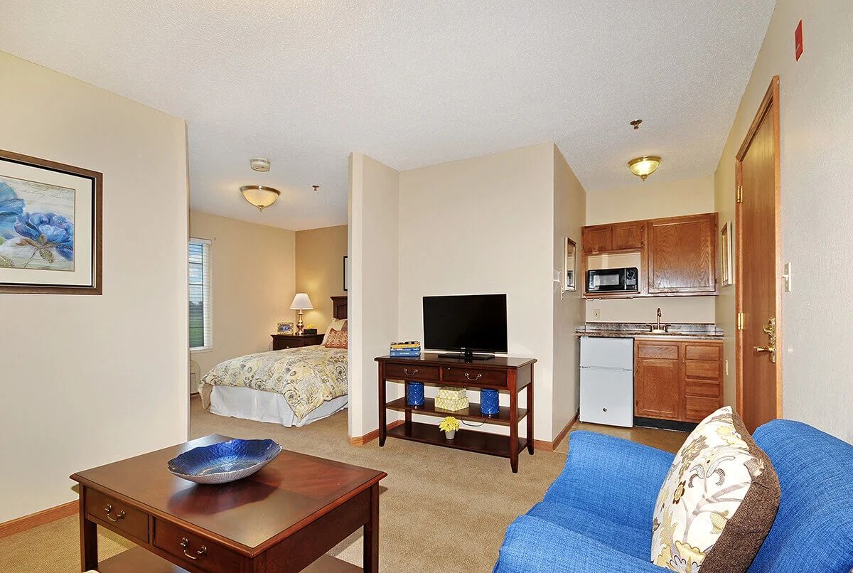 A cozy studio apartment featuring a combined living space with a kitchenette, small dining area, and sleeping area.