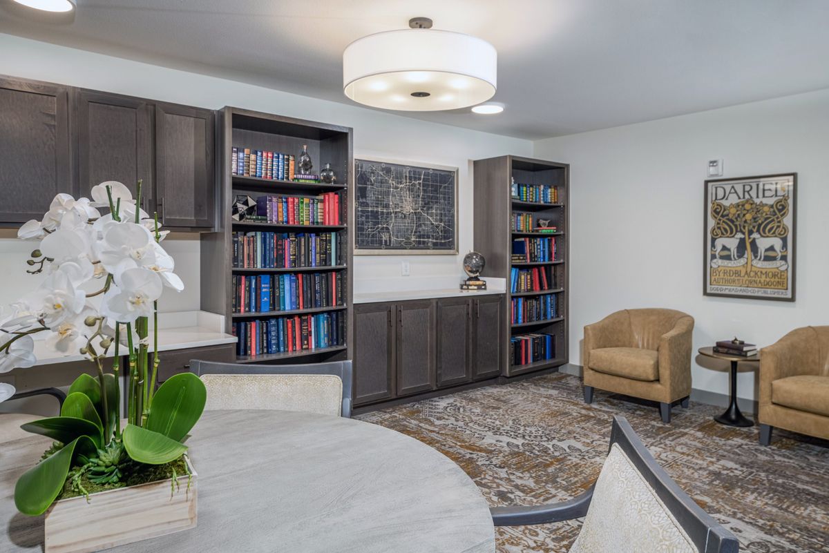 A cozy library space featuring bookshelves filled with books, a comfortable armchair, and modern lighting.