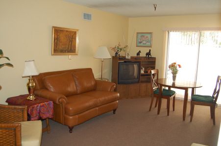 A cozy living room with a leather sofa, television, and a small dining table.