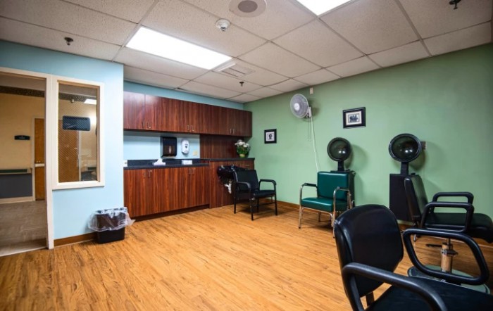 A cozy salon interior with chairs and hair dryers, featuring wooden flooring and cabinets.