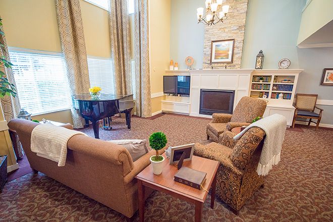 A cozy living room featuring a fireplace, comfortable seating, and a grand piano.