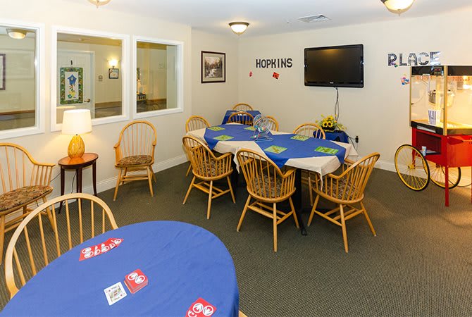 A cozy card game room with tables, chairs, and a television.