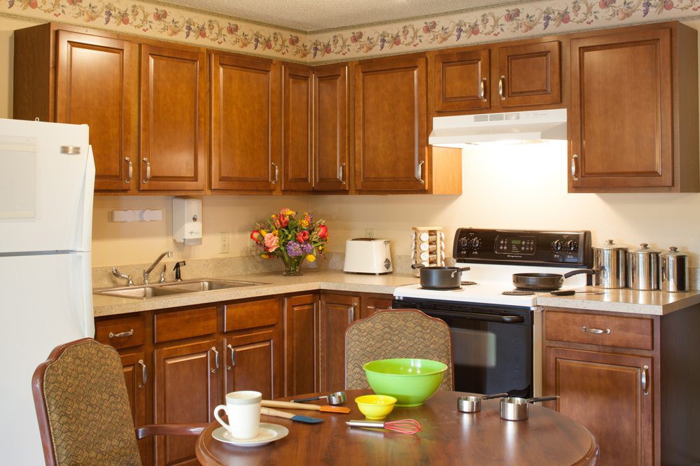 A cozy kitchen with wooden cabinets, a stovetop, and a dining table set with dishes.
