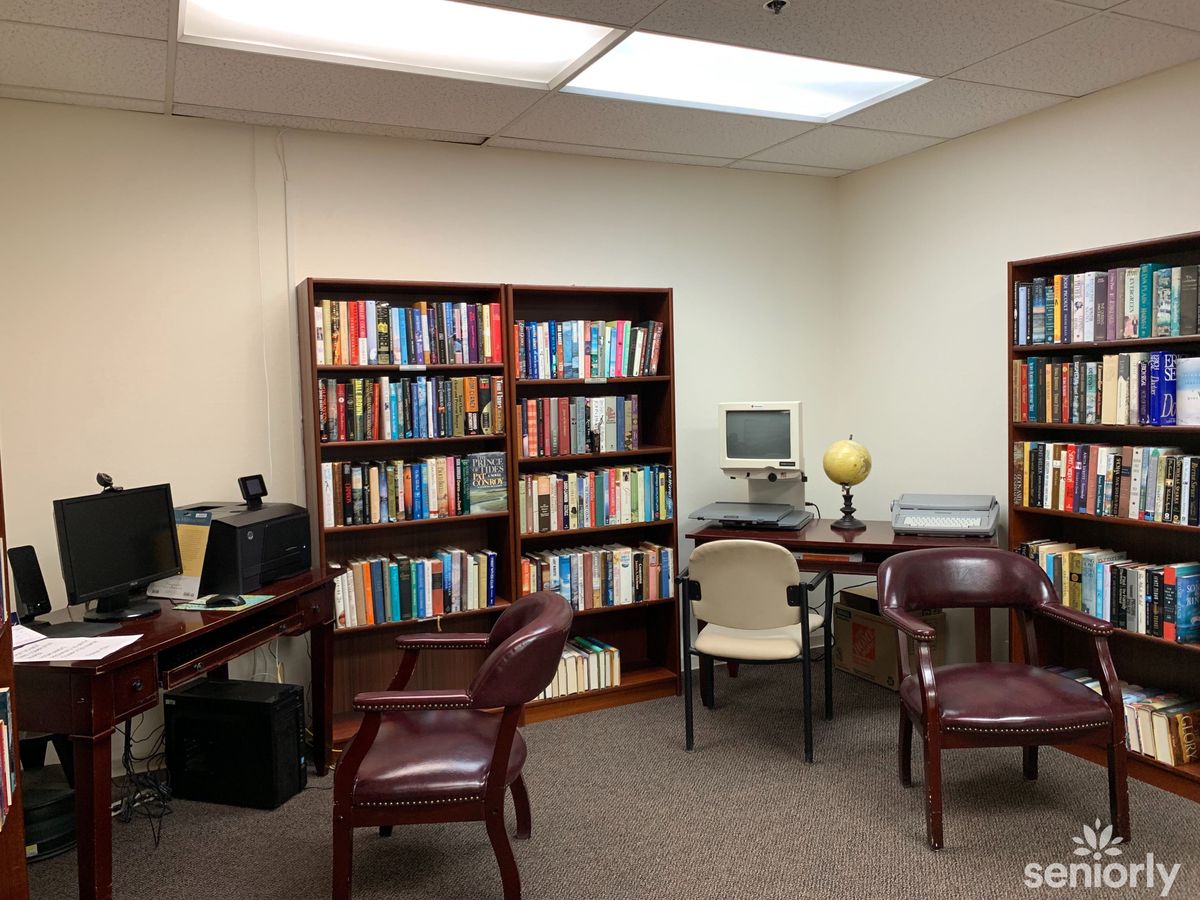 An office space with bookshelves, leather chairs, and a computer on a desk.