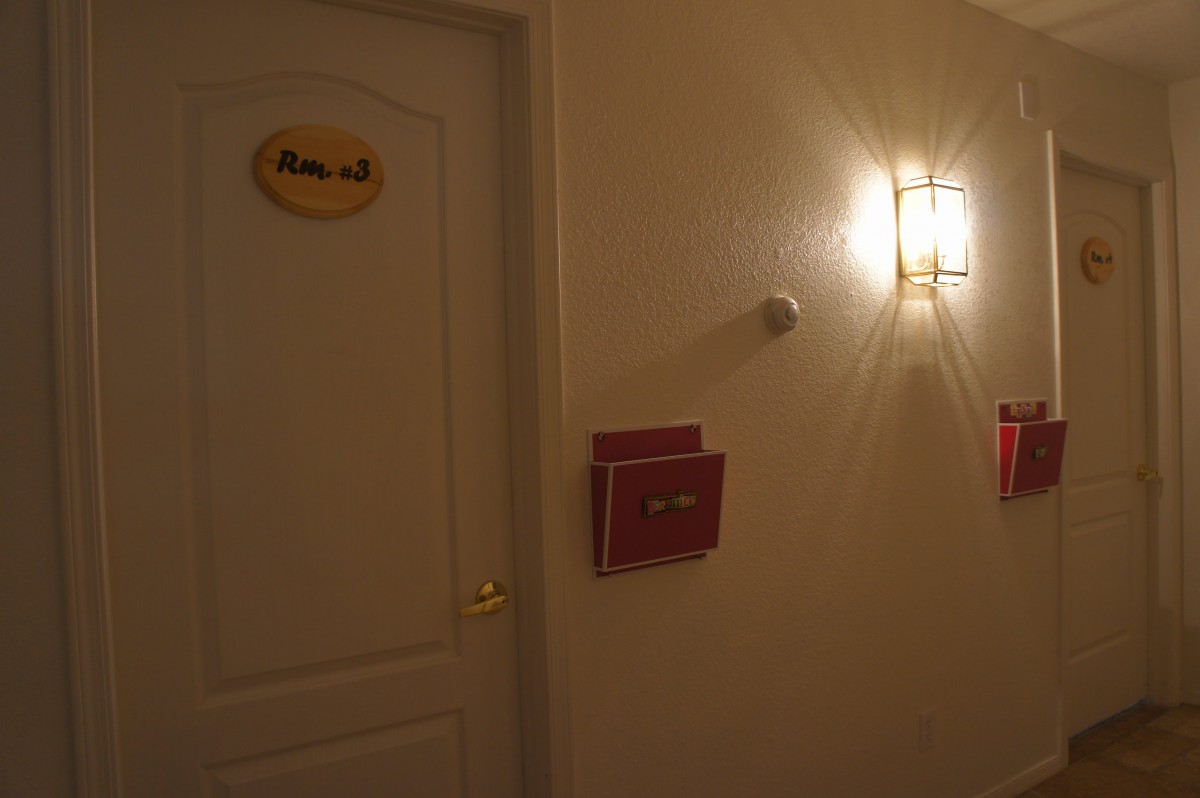 A dimly lit hallway with a closed door and a wall-mounted light fixture.