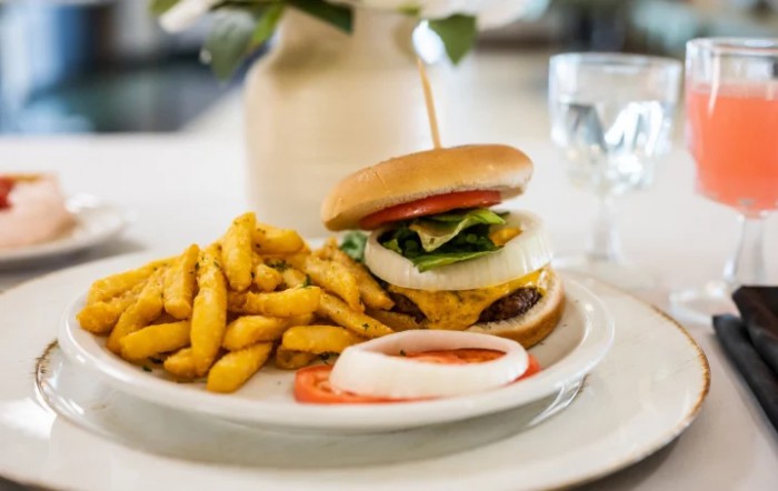 A delicious burger served with crispy fries on a white plate.