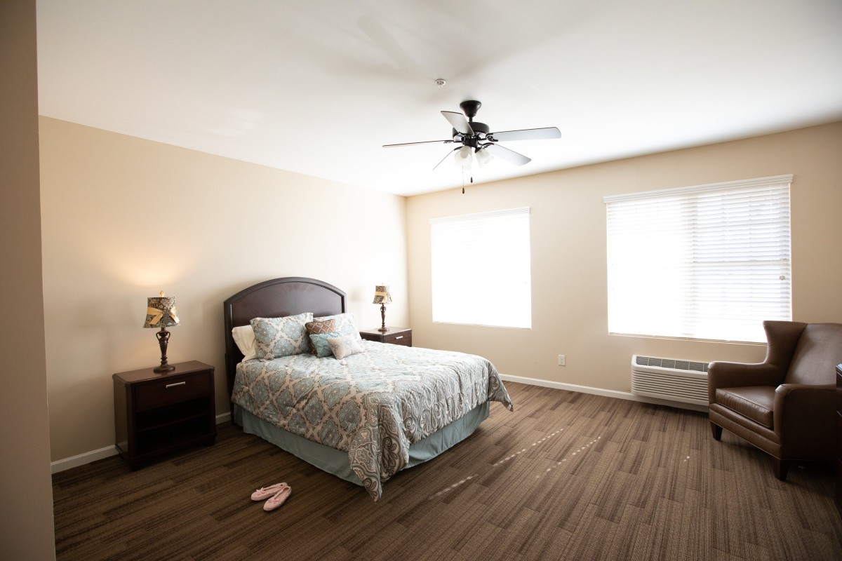 A minimalist bedroom with a bed, nightstands, and a ceiling fan.