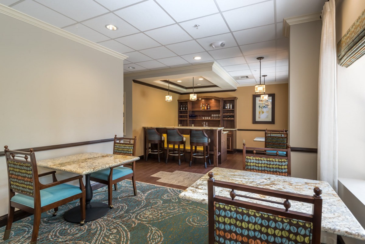 A cozy lobby seating area with tables, chairs, and warm lighting.