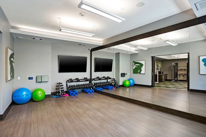 A modern fitness studio with mirrors, dumbbells, and exercise balls.
