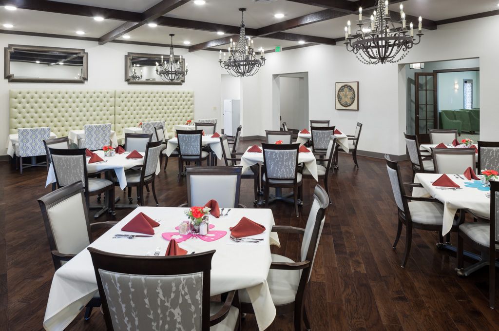 An elegant dining room with neatly arranged tables and chandeliers.