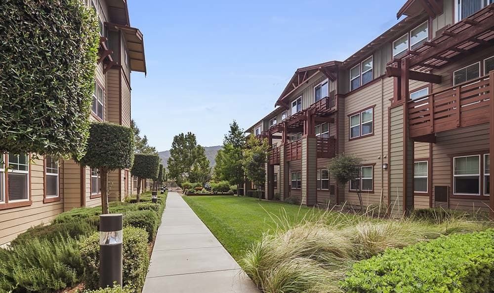 A modern apartment complex with neatly maintained landscaping and a central pathway.