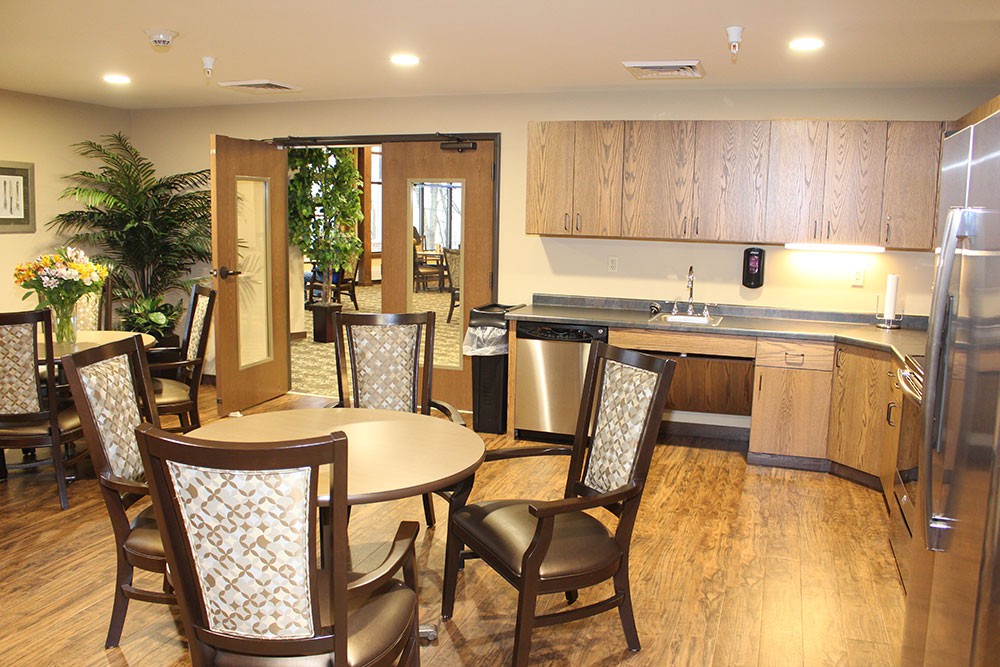 Modern kitchen and dining area with wooden flooring and elegant furniture.