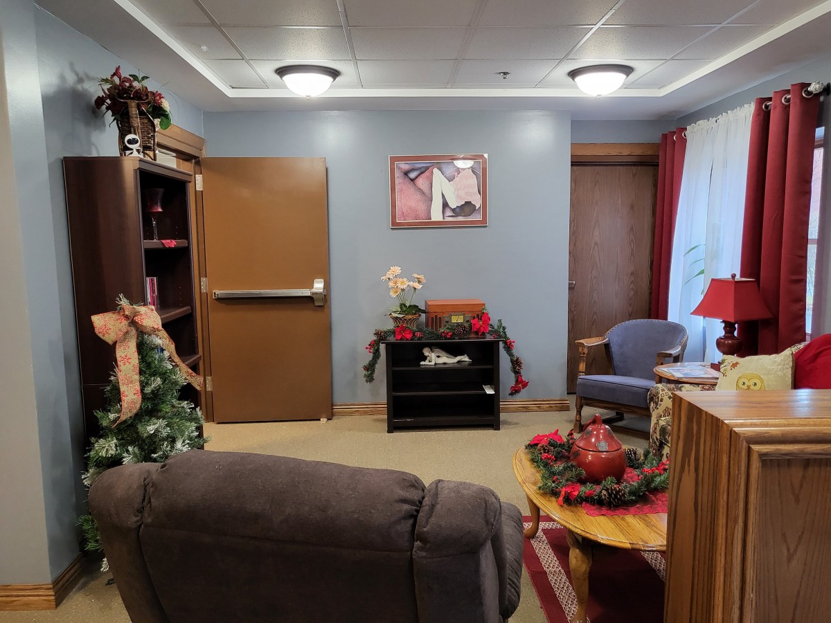A cozy living room decorated for Christmas with a comfortable chair, small table, and festive ornaments.