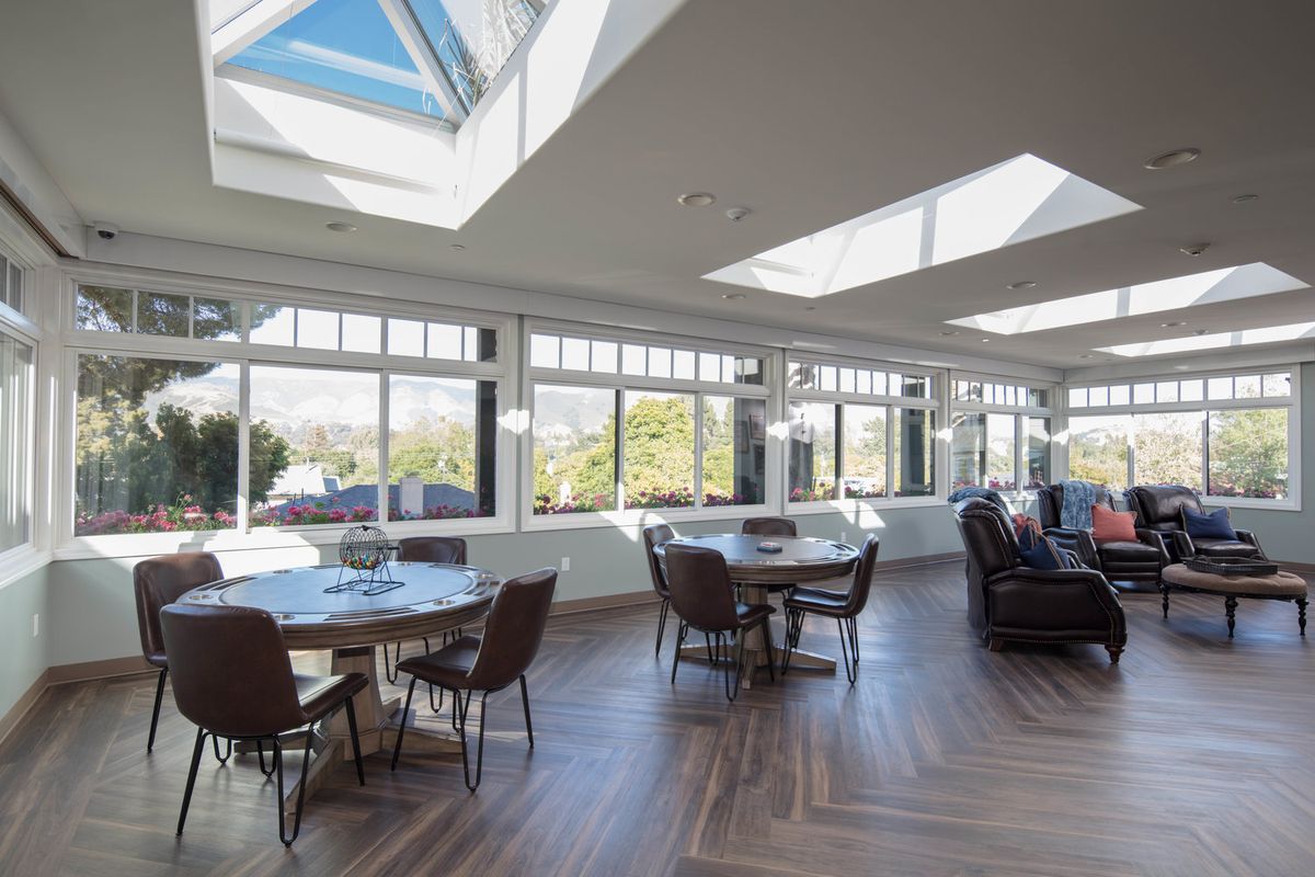 A spacious dining and living area with large windows and skylights flooding the room with natural light.