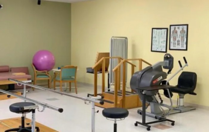 A physical therapy room equipped with exercise machines and a fitness ball.