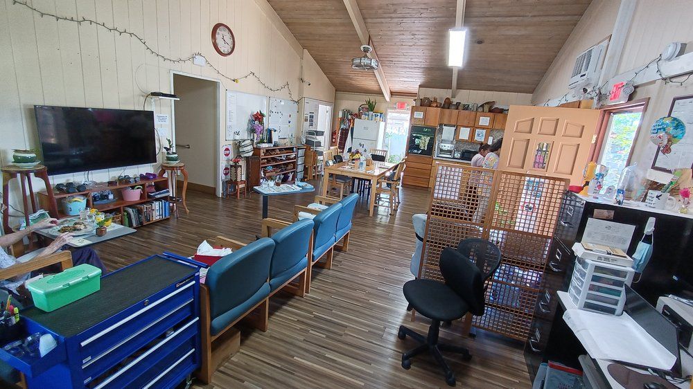 An office interior with a waiting area featuring chairs, desks, and a wooden floor.