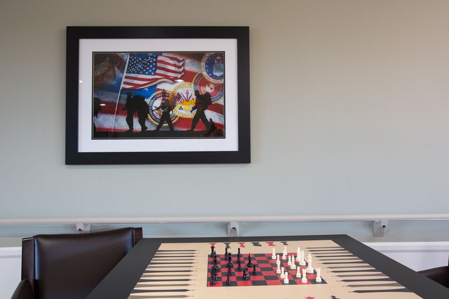 A room featuring a chessboard on a table and a framed artwork with flags on the wall.