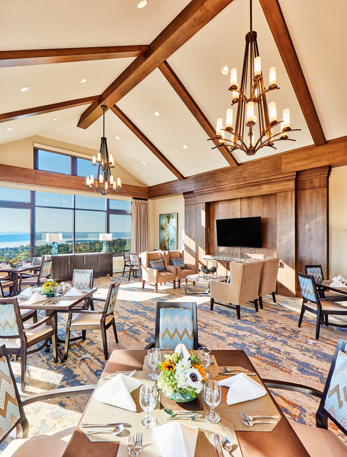 A luxurious dining room with large windows, elegant chandeliers, and comfortable seating.