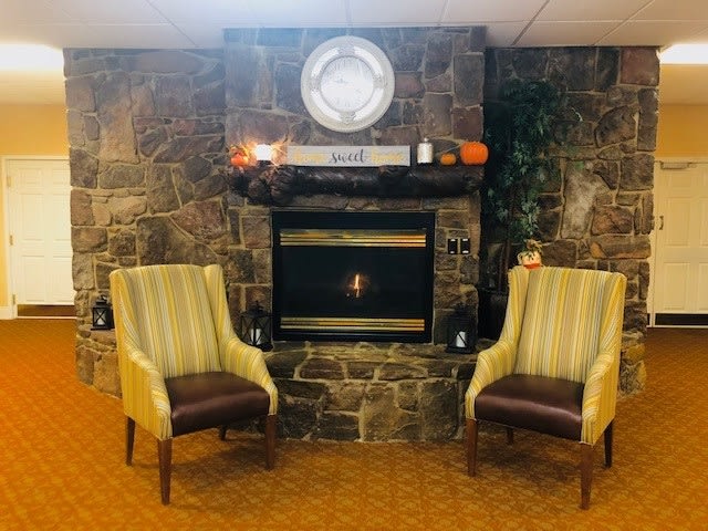 A cozy living area featuring a stone fireplace with two upholstered chairs placed symmetrically.