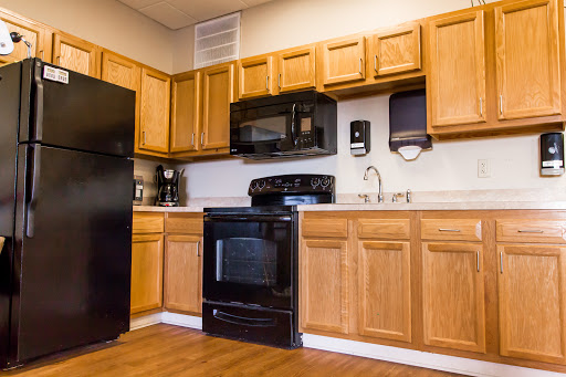 A modern kitchen featuring wooden cabinets and black appliances.
