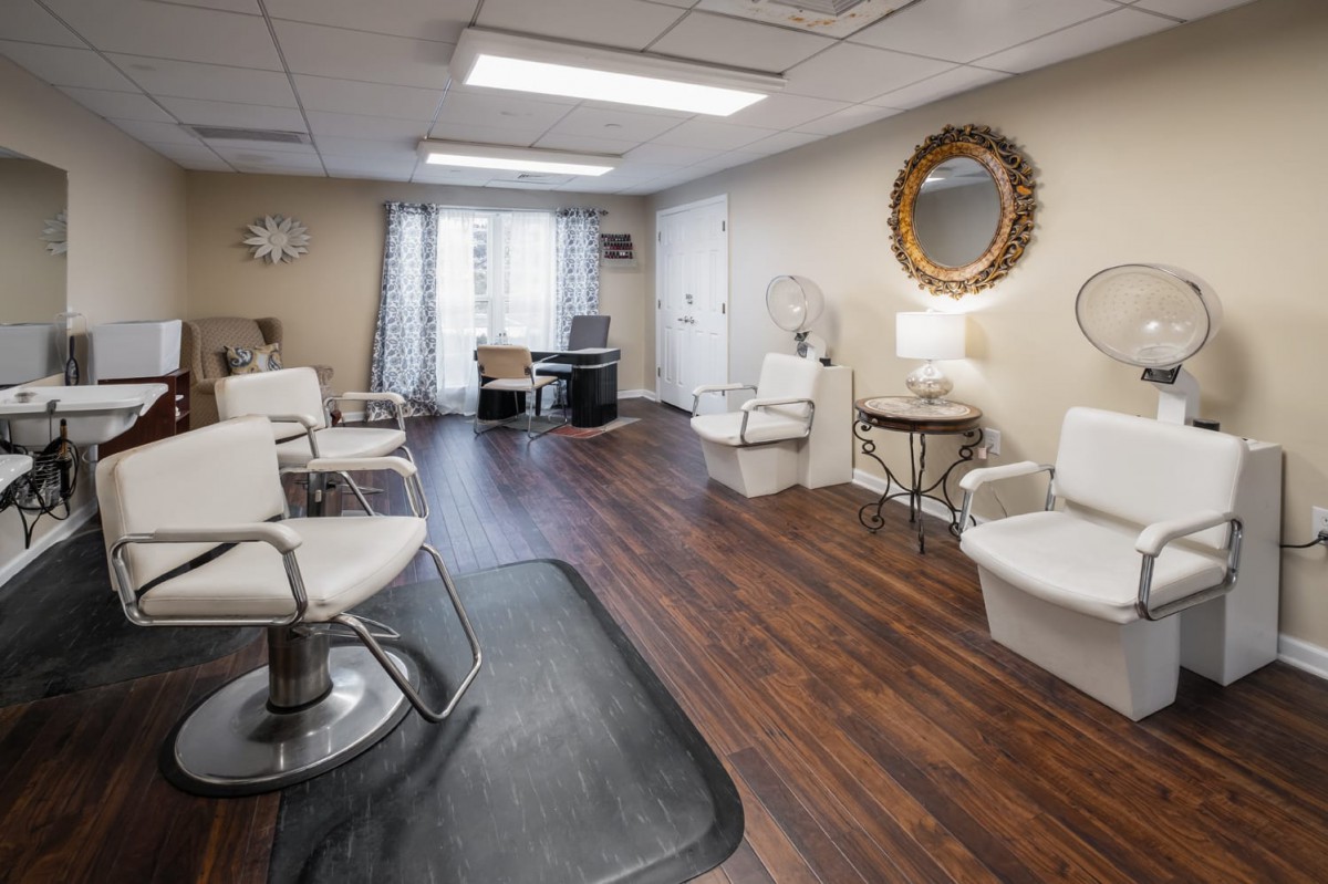 A modern beauty salon interior with comfortable chairs and mirrors on hardwood flooring.