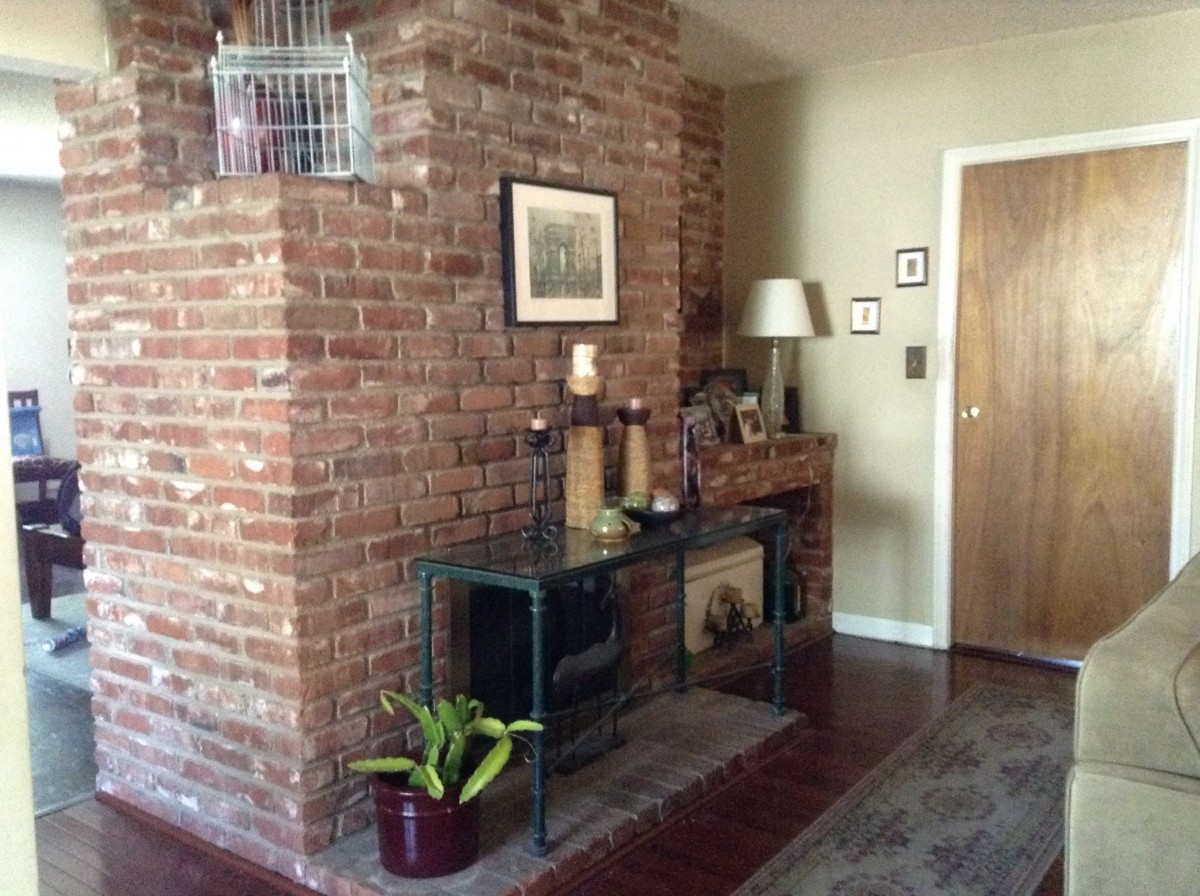 A cozy living room corner with a brick wall, decorated with art and furnishings.