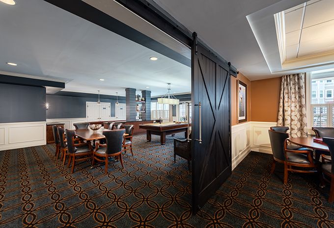 A modern game room featuring a pool table and seating area, divided by a stylish barn door.
