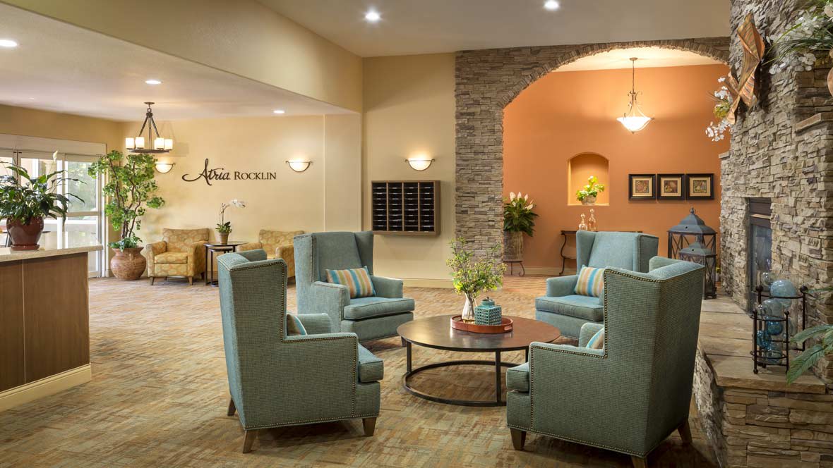 A cozy lobby area featuring blue armchairs and a circular coffee table.