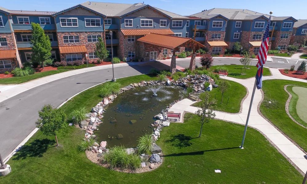 A scenic view of a building entrance surrounded by a landscaped garden with a pond.